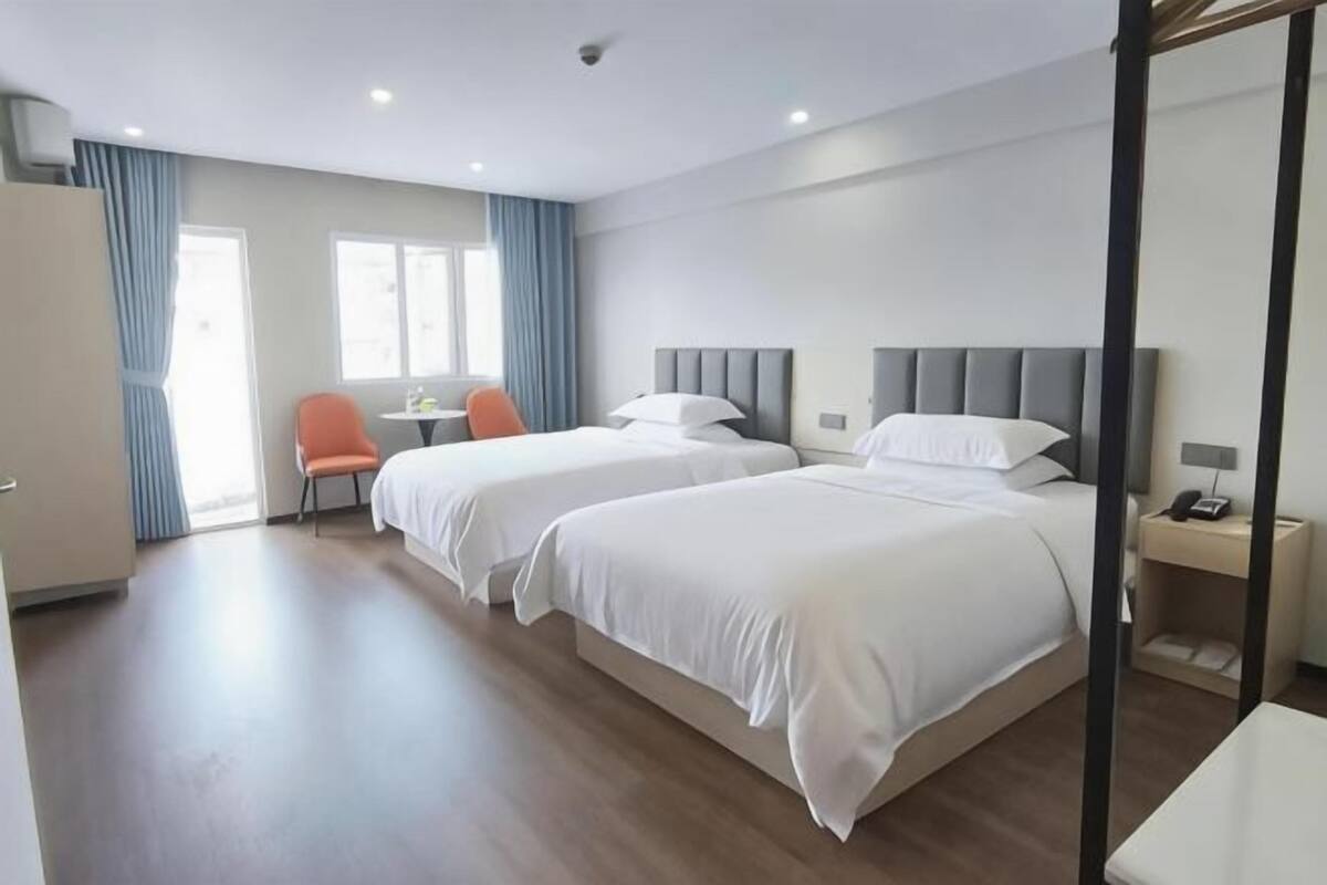 Een hotelkamer met twee bedden, een bureau, een stoel en een badkamer.