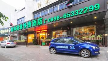 A hotel with a storefront and a blue car parked in front.