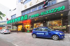 Un hotel con escaparate y un coche azul estacionado frente a él.