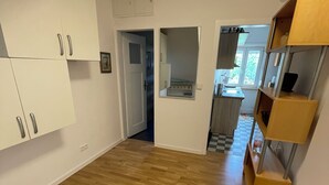 A spacious room with wooden flooring, white walls, and built-in cabinets. There is a small kitchenette area with a sink and a window. - Comfortable 2-bedroom apartment with WiFi in Lovely Plieningen! (Stuttgart)