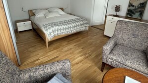 A bedroom with a bed, bedside tables, a chair, a desk, and a door. - Comfortable 2-bedroom apartment with WiFi in Lovely Plieningen! (Stuttgart)