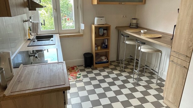 A compact kitchen with a checkered floor, a window, and a built-in microwave. - Comfortable 2-bedroom apartment with WiFi in Lovely Plieningen! (Stuttgart)