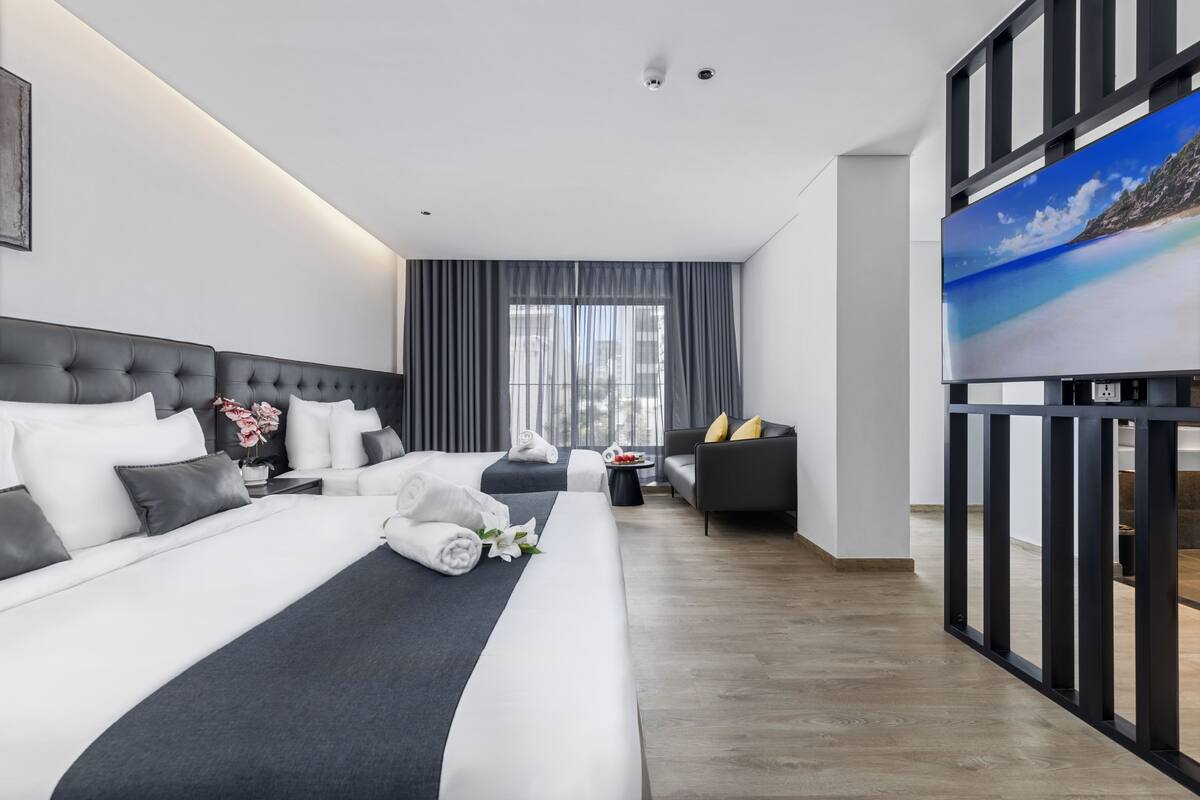 Une chambre d’hôtel moderne, dotée d’un grand lit, d’un canapé, d’une télévision et offrant une vue sur l’extérieur.