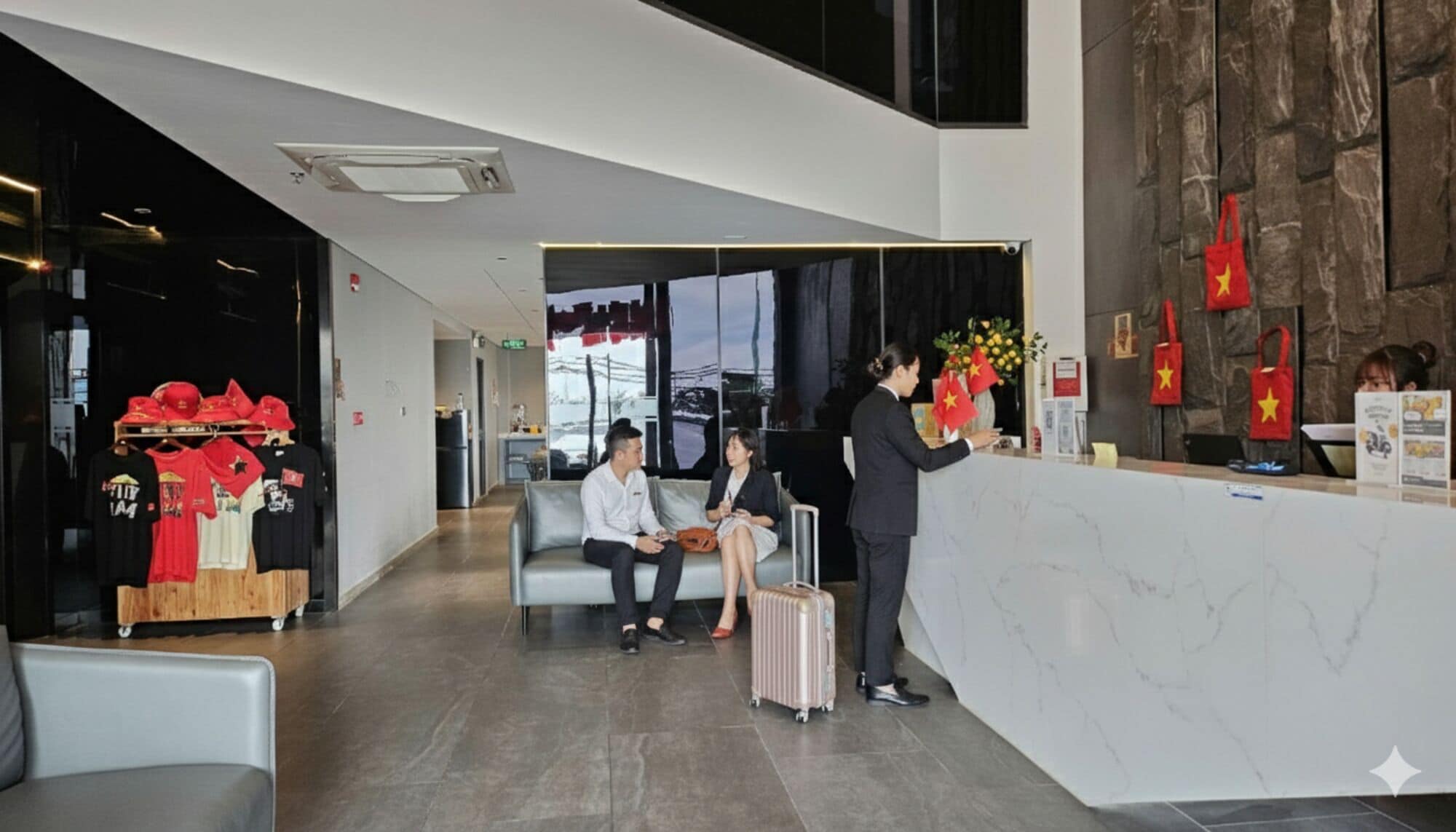 Zona de recepción de un hotel con mostrador de mármol, área de descanso con sofá y exhibición de productos.
