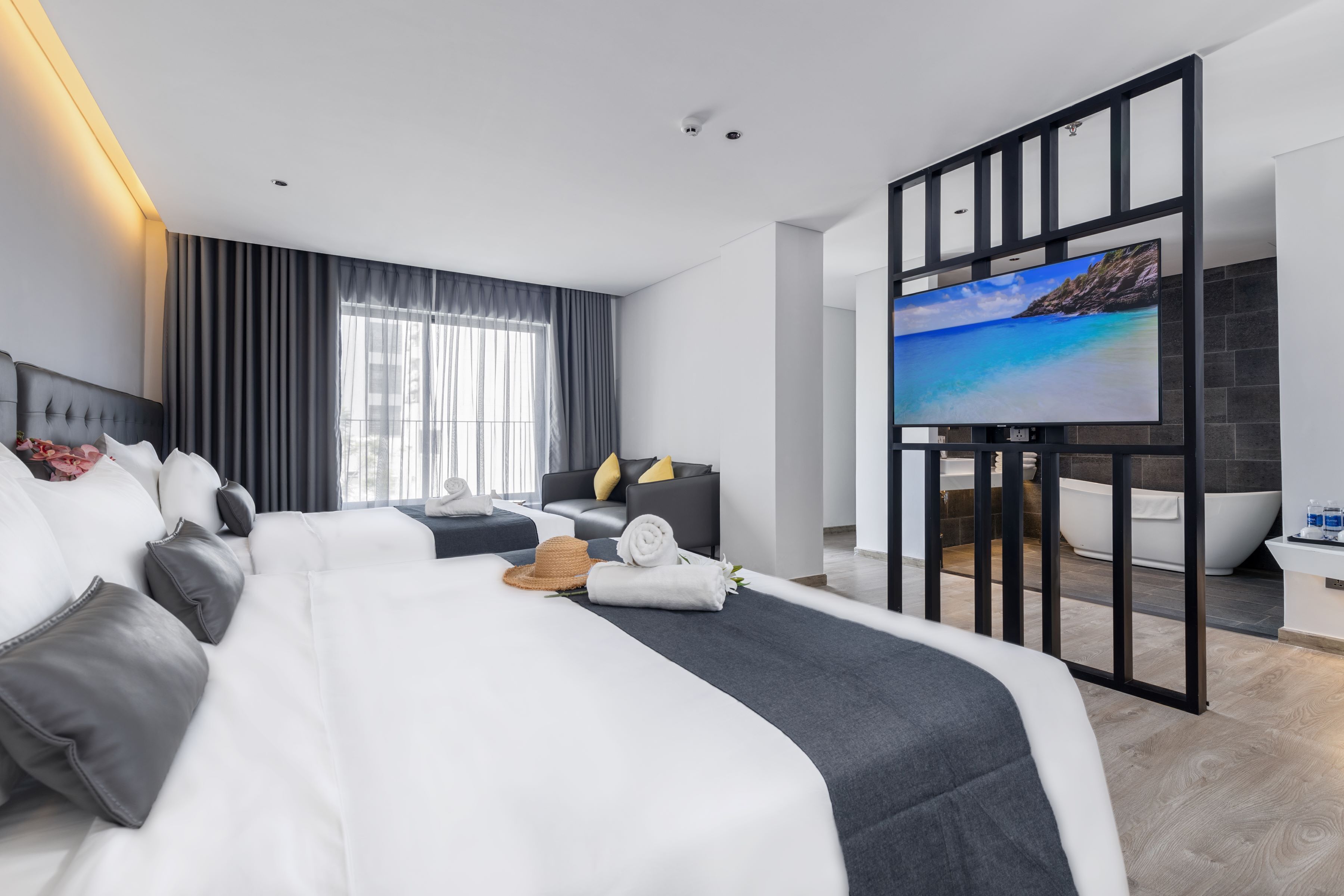 Una habitación de hotel moderna con una cama grande, un televisor, un sofá y una bañera.