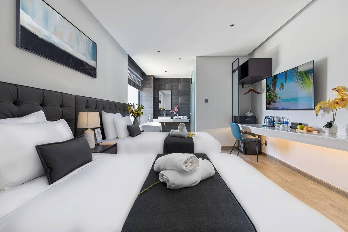 Une chambre d’hôtel moderne équipée d’un grand lit, d’un bureau, d’une chaise et d’un téléviseur.
