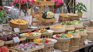 Un bufé con diversos platos y frutas frescas presentadas en cestas y recipientes de madera.