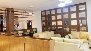 A modern bar area with wooden partitions and a seating area with a cream-colored sofa. - De Palms Hotel Port Harcourt (Port Harcourt)