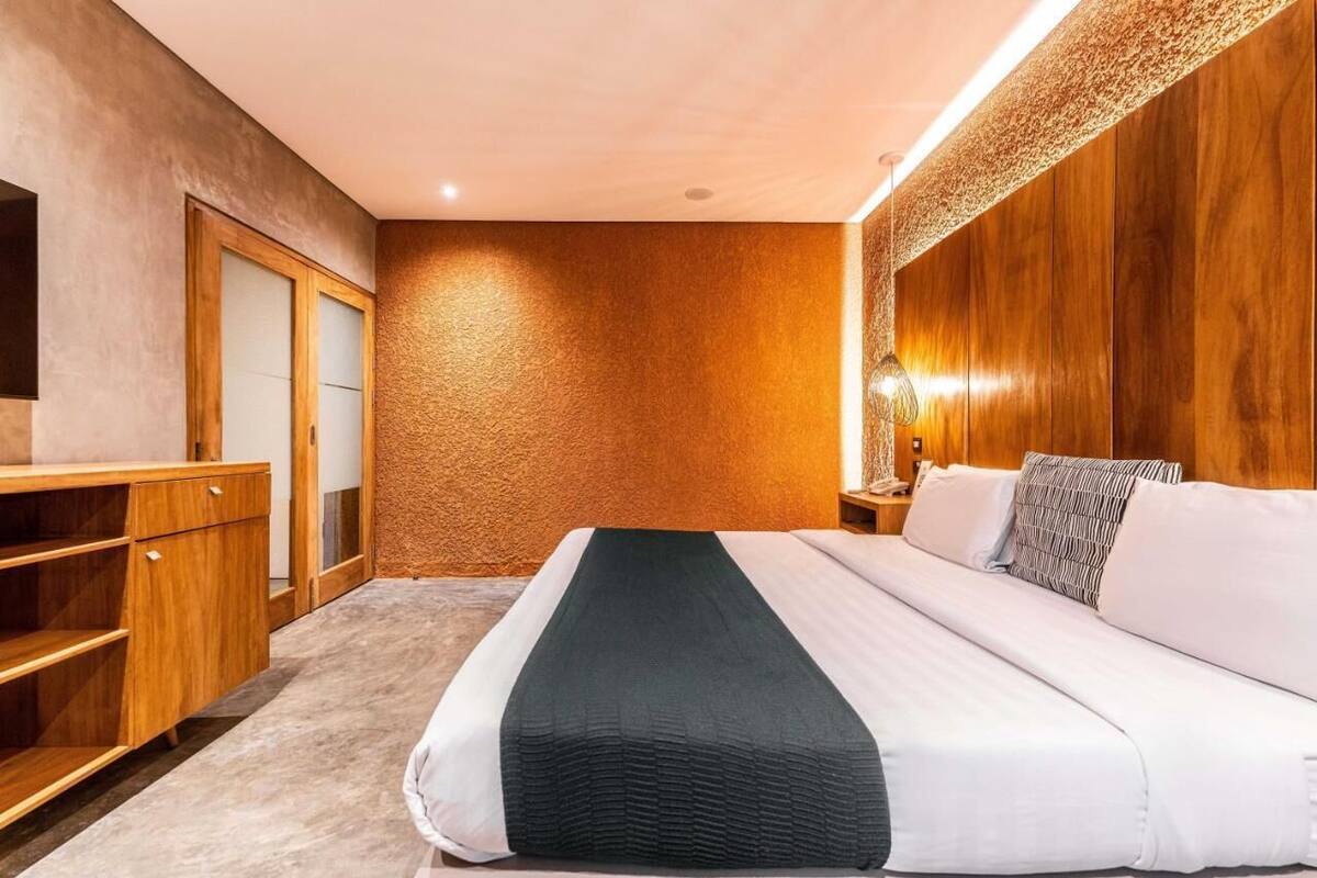 Una habitación de hotel con cama, armario de madera y mesita de noche con lámpara.