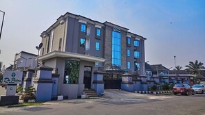 A multi-story hotel with a central entrance, a gated driveway, and a parking area. - De Palms Hotel Port Harcourt (Port Harcourt)