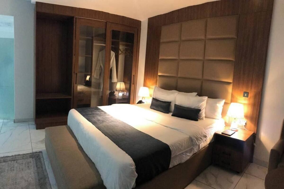 Un dormitorio con una cama grande, un armario y una mesita de noche con una lámpara.