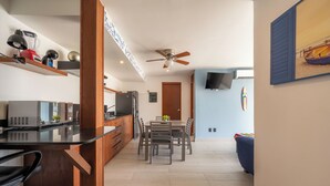 A modern kitchen with a black countertop, wooden cabinets, and a built-in microwave. There is a dining area with a table and chairs, and a ceiling fan above. - Eden in the heights. Terrace and private pool centre and playa (Playa del Carmen)
