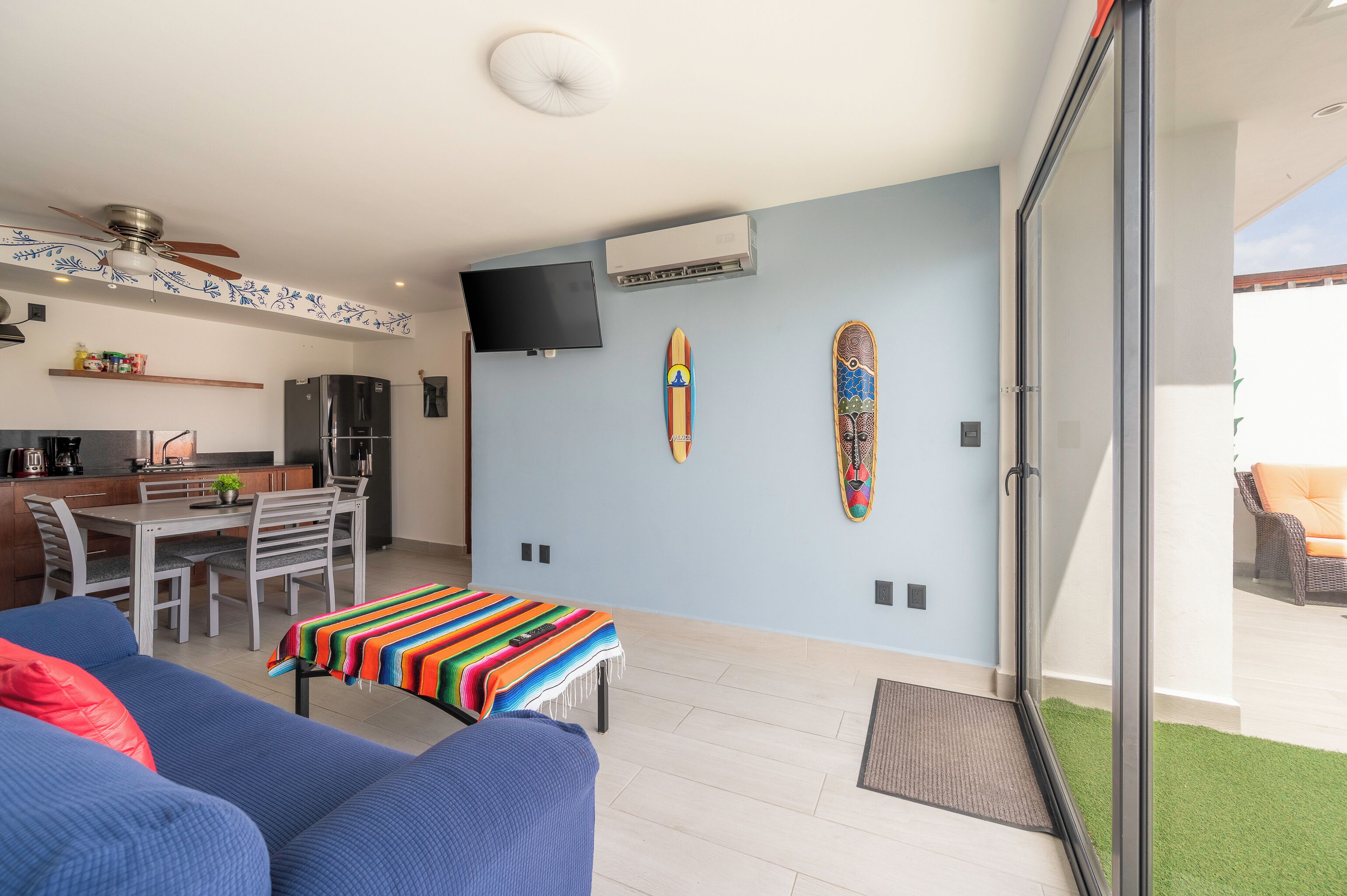 A modern living space with a dining area, a sofa, a TV, and a balcony with a view.