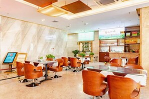 A hotel dining area with round tables, brown chairs, and a marble wall. - Hainan Hongyun Hotel (Haikou Qilou Old Street) (Haikou)