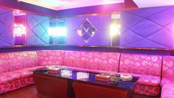 A room with a pink patterned sofa, a glass-top coffee table, and a wall with geometric patterns.