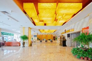 Un hall d’hôtel avec un sol en marbre, un comptoir d’accueil et des plantes en pot.