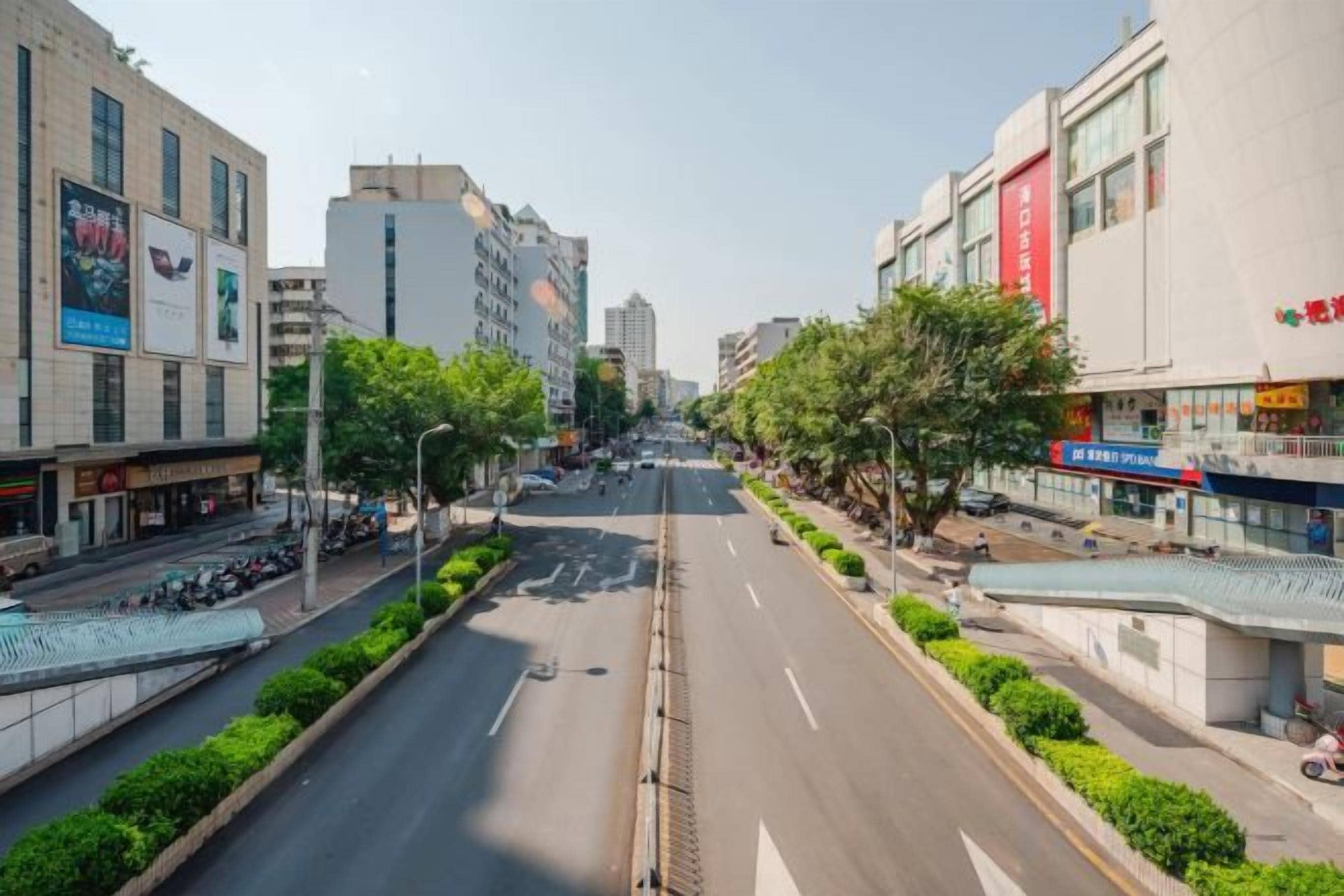 A wide urban street with buildings on both sides, a clear sky, and no visible people or vehicles.