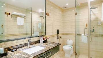 Un baño moderno con ducha de vidrio, lavamanos de mármol y un espejo grande.