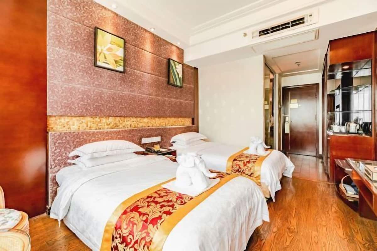 Hotellihuone, jossa on kaksi sänkyä, puulattia, marmoriseinä ja taulu.