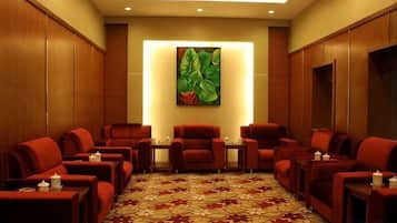 A room with multiple red chairs and tables, a patterned floor, and a large painting on the wall.