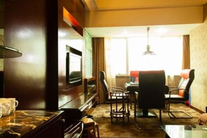 A hotel room with a flat-screen TV, a dining table with chairs, a sofa, and a large window with curtains. - Hainan Hongyun Hotel (Haikou Qilou Old Street) (Haikou)