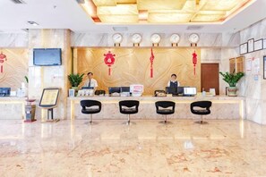 A hotel reception area with a marble floor, a reception desk, and three black chairs. - Hainan Hongyun Hotel (Haikou Qilou Old Street) (Haikou)