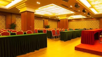 A conference room with multiple tables and chairs, a stage, and a patterned wall.