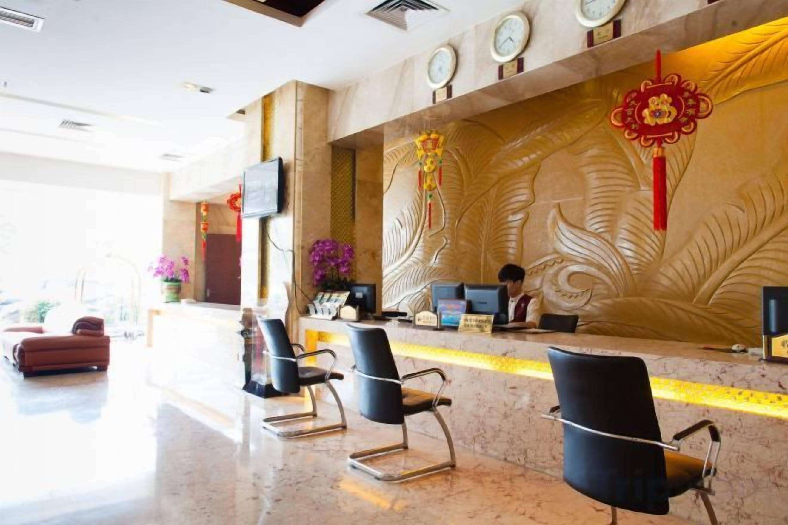 Ein Hotel-Empfangsbereich mit Marmorboden, einer Rezeption und einer Sitzecke.