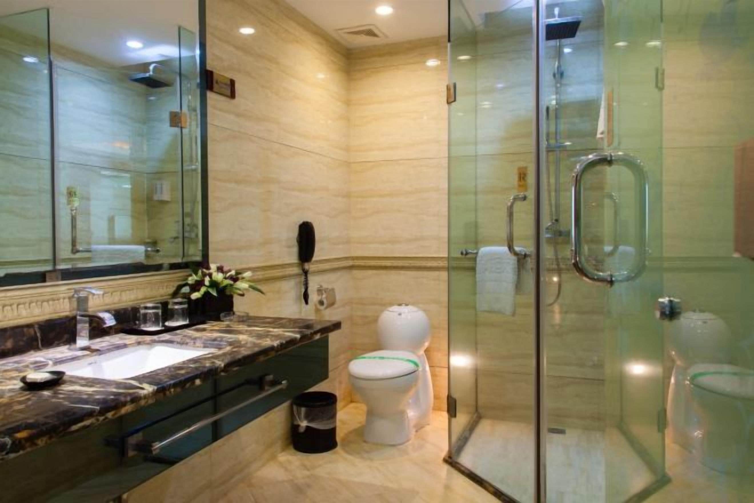 Un baño moderno con ducha de vidrio, lavamanos de mármol y retrete.