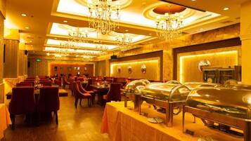 A banquet hall with round tables, chairs, and buffet stations.