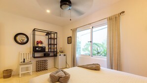 Une chambre d’hôtel avec un grand lit, un petit bureau, un miroir et une fenêtre avec des rideaux.