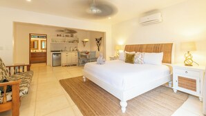 Een slaapkamer met een groot bed, nachtkastjes, een ventilator in het plafond en een airconditioning.