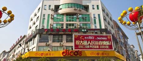 Un edificio de varios pisos con señalización comercial en la planta baja, incluyendo un llamativo letrero que dice 'dicos'.