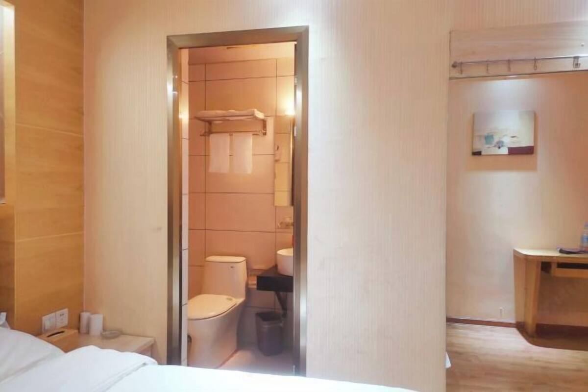 Una habitación de hotel con una cama, un baño con inodoro y lavamanos, y un escritorio pequeño.