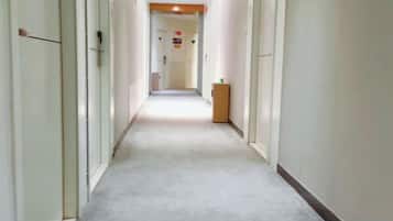 A long, narrow hallway with doors on both sides, leading to a room at the end.