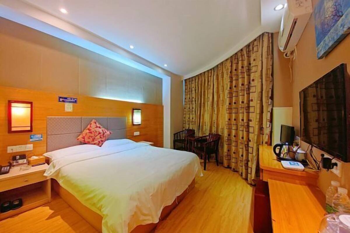 Una habitación de hotel con una cama grande, una mesita de noche y un escritorio con una silla.