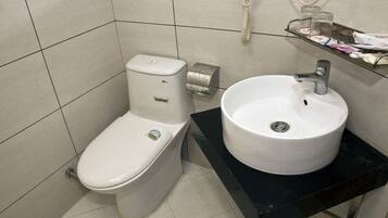 A bathroom with a toilet, sink, and a telephone mounted on the wall.