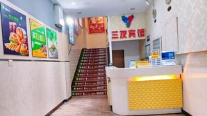Zona de recepción con mostrador, escalera y varios carteles en la pared.