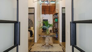 A hallway with a wooden ceiling, a central table with a vase, and a bookshelf. - Casa Primos - Luxury Home, Casa Primos - Luxury Home - 2 Min Walk to the Beach (Nosara)