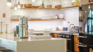 A modern kitchen with wooden beams, a central island, hanging pendant lights, and a built-in oven. - Casa Primos - Luxury Home, Casa Primos - Luxury Home - 2 Min Walk to the Beach (Nosara)