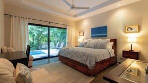 Une chambre moderne avec un grand lit, un ventilateur de plafond, un bureau et une vue sur l’extérieur.