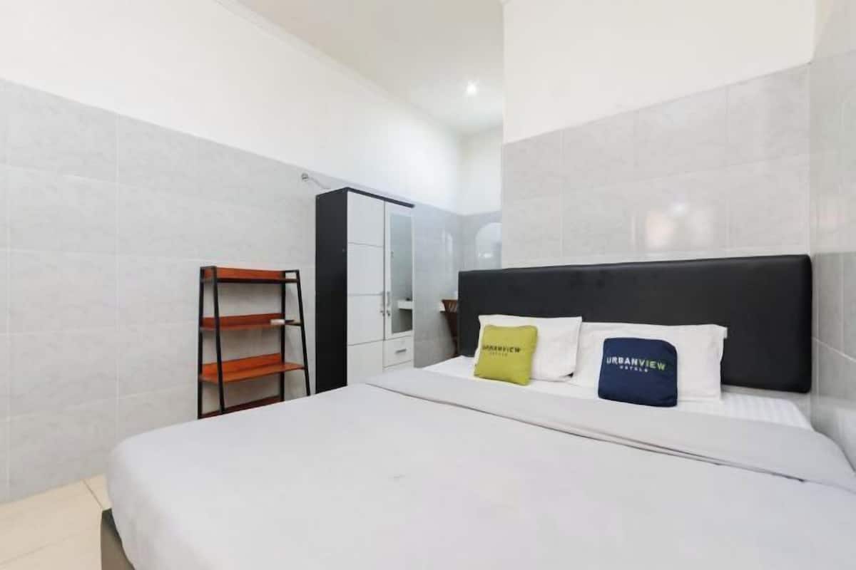 A hotel room with a bed, a wardrobe, and a shelf unit.
