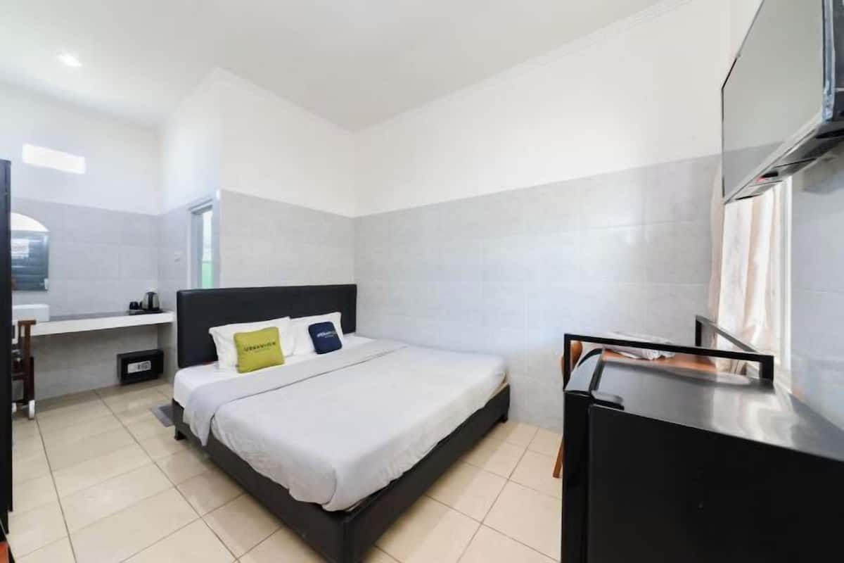 A modern hotel room with a bed, a desk, and a TV.