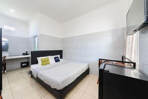 Een moderne hotelkamer met een bed, een bureau en een televisie.