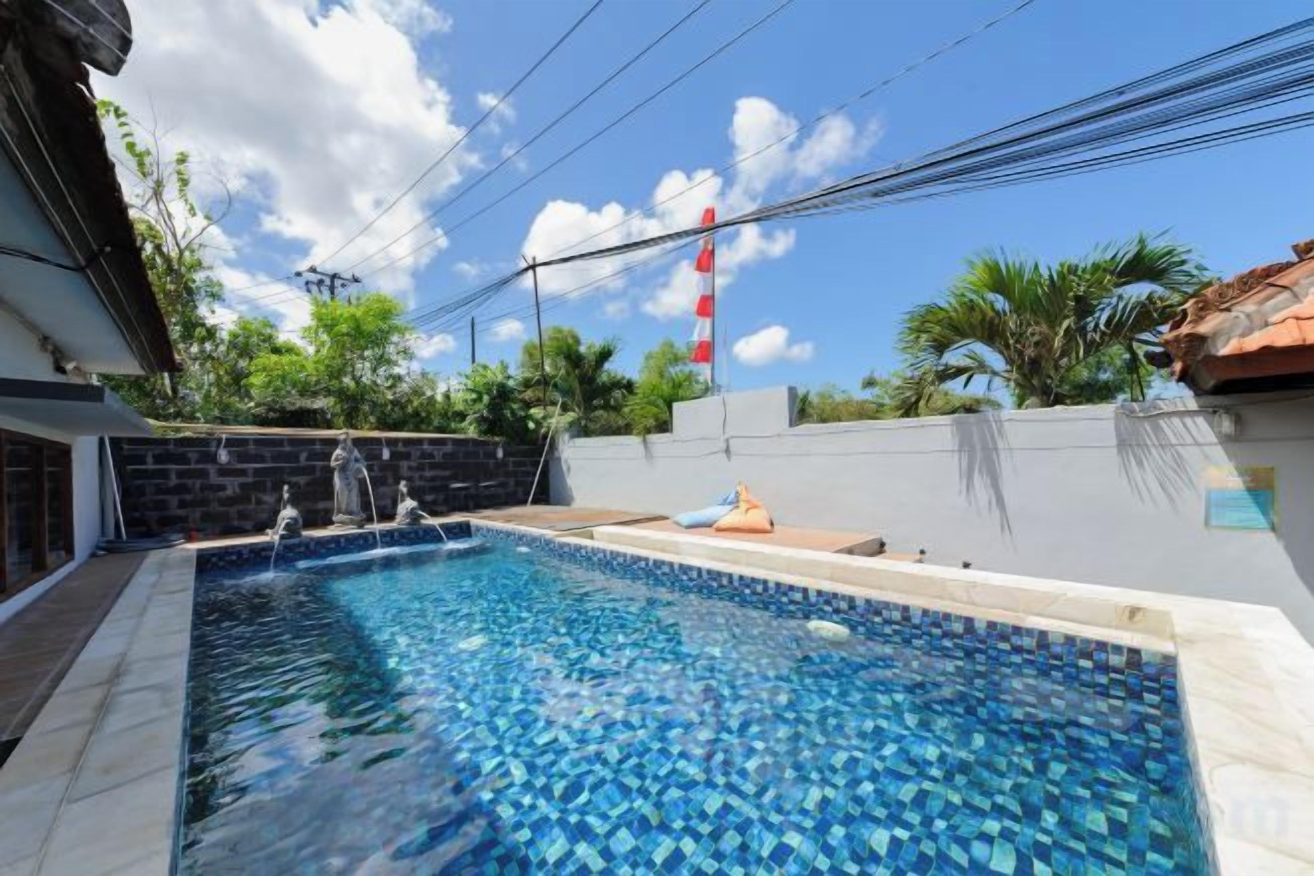 A swimming pool with a tiled edge, surrounded by a low wall and a clear sky.