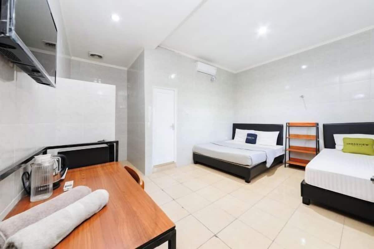 A hotel room with a wooden table, a bed, a TV, and a window.