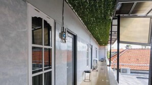 Un pasillo con suelo de baldosas, un banco negro y una ventana que da a un tejado rojo de tejas.