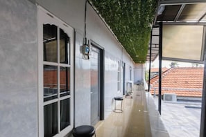 A corridor with a tiled floor, a bench, a door, and a window with a view of a red-tiled roof. - Urbanview Ava Guest House Uluwatu Bali (Bali)
