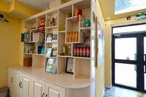 A reception area with a counter, shelves with various items, and a door to the right.