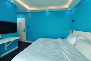 A hotel room with a bed, a TV, and a door. - Wuwangwo Hotel (Burqin)